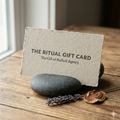 The Ritual Gift Card on a wooden surface with a stone and lavender.