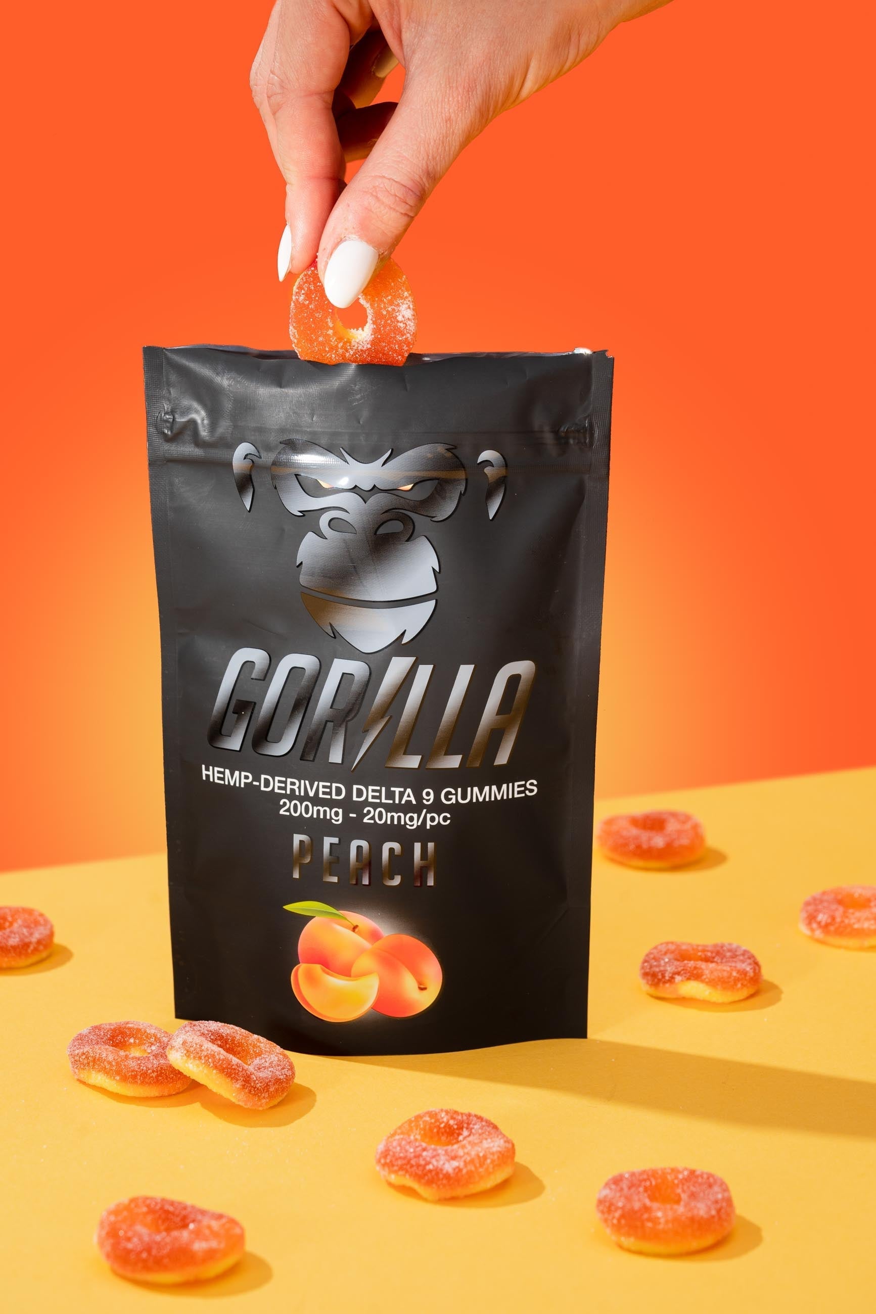 Gorilla brand gummy bear packaging with a hand holding a gummy bear on an orange and yellow background.