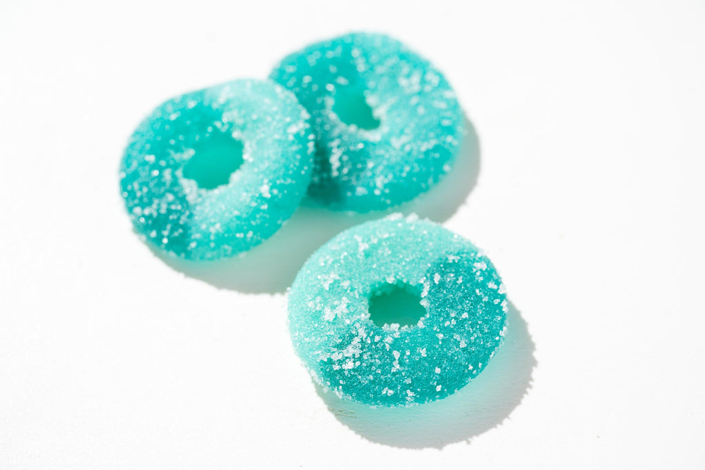 Three turquoise gummy donuts with a white background