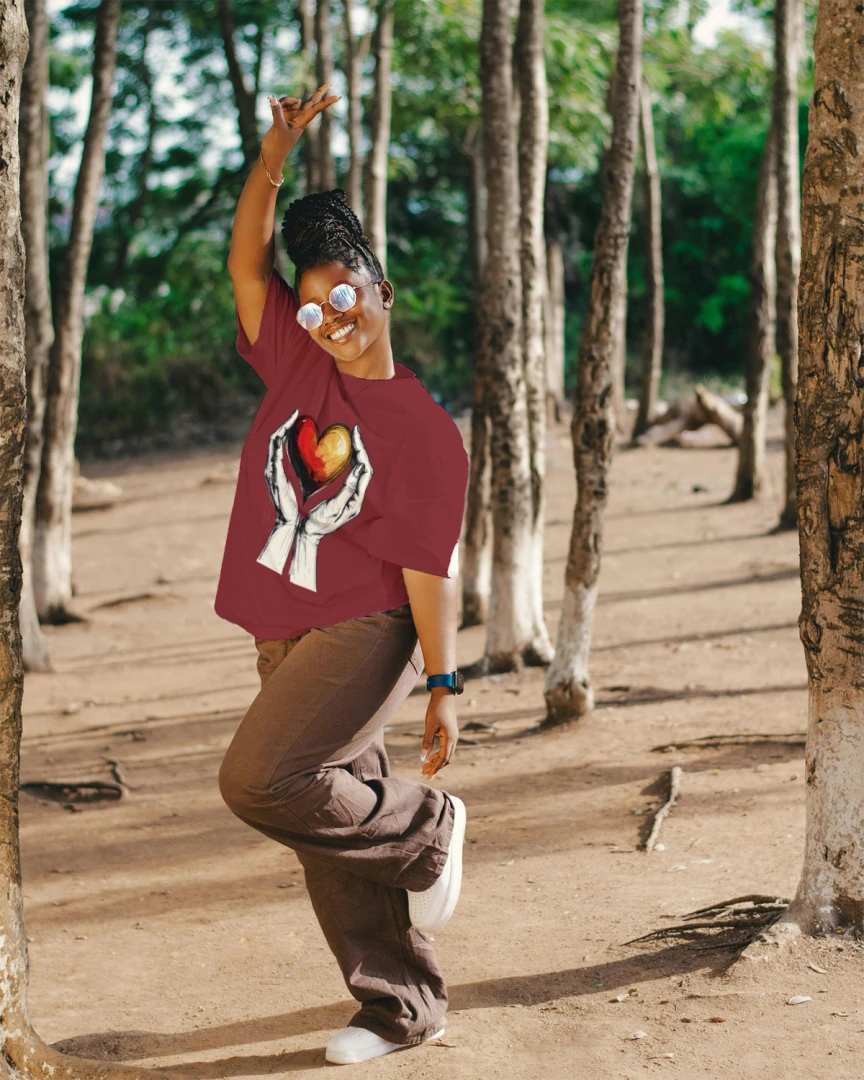 Person wearing a red shirt with a graphic design, standing in a forested area.