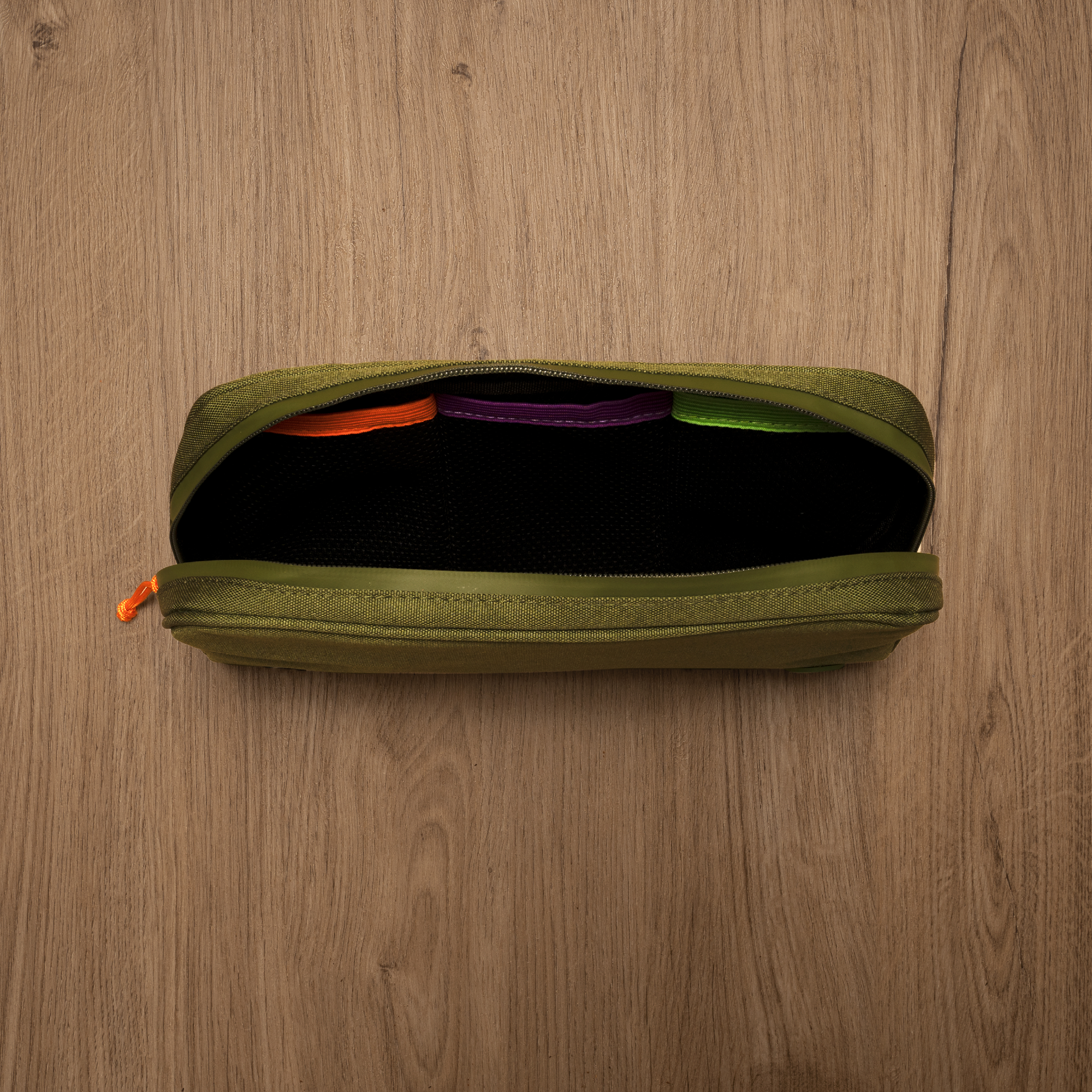 Green pouch with colorful items on a wooden surface
