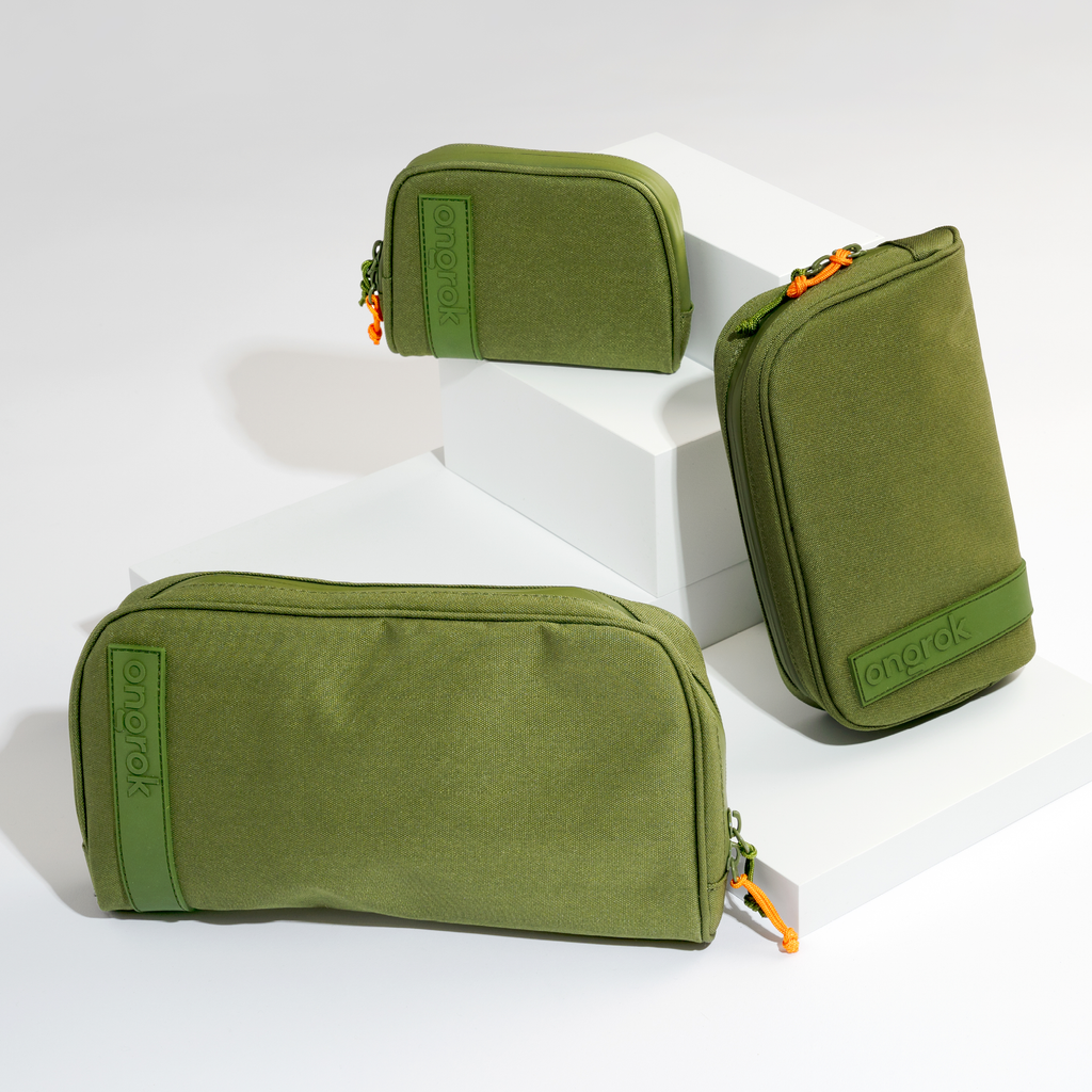 Three green travel bags with orange zippers on a white background