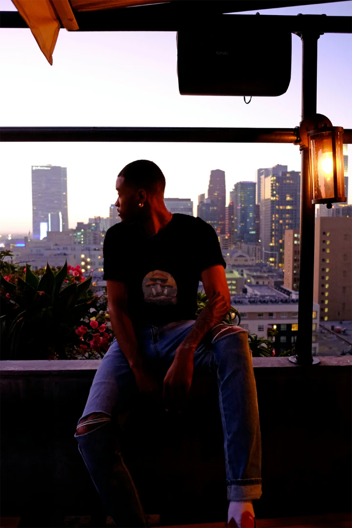 Person sitting on a rooftop with a city skyline in the background