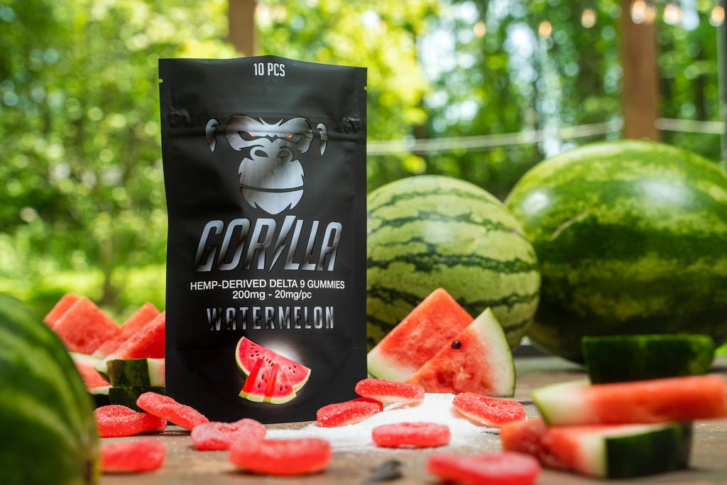 Gorilla brand watermelon gummy package with watermelons and gummies on a table outdoors.