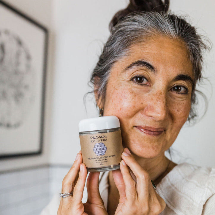 Woman holding a PAAVANI Ayurveda product in front of her face