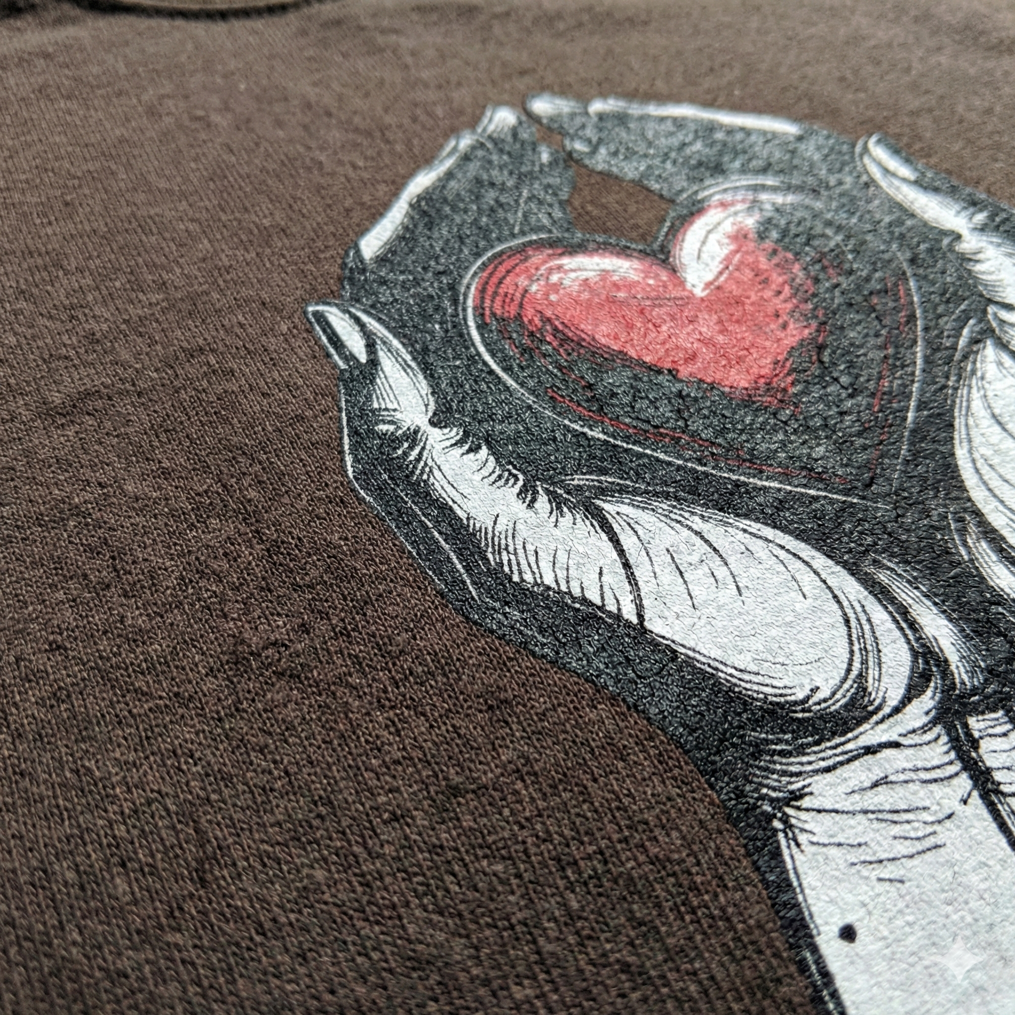 Close-up of a graphic design on a shirt with a hand holding a heart.