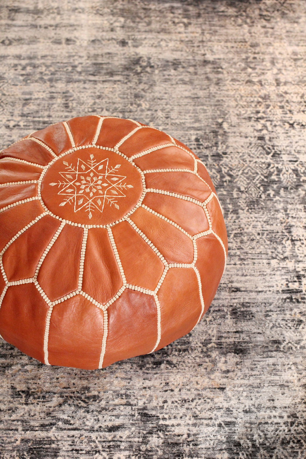 Brown leather pouf with a star pattern on a textured surface