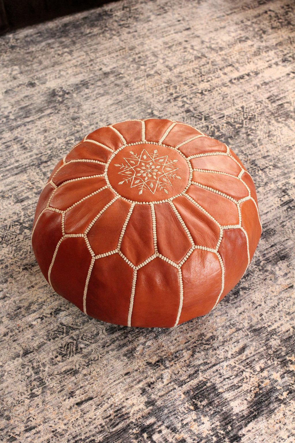 Brown leather ottoman with intricate patterns on a marble surface