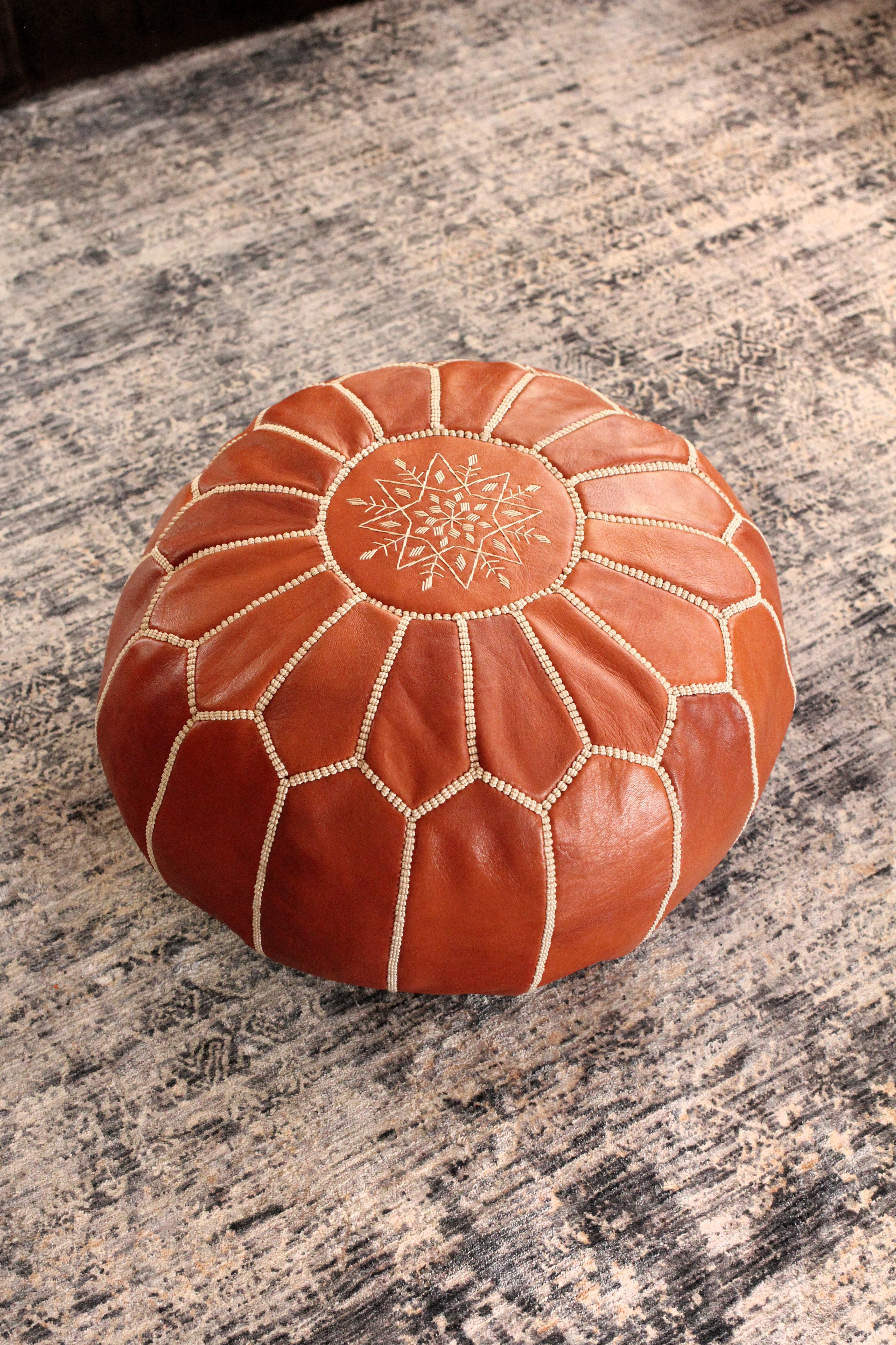 Brown leather ottoman with intricate patterns on a marble surface