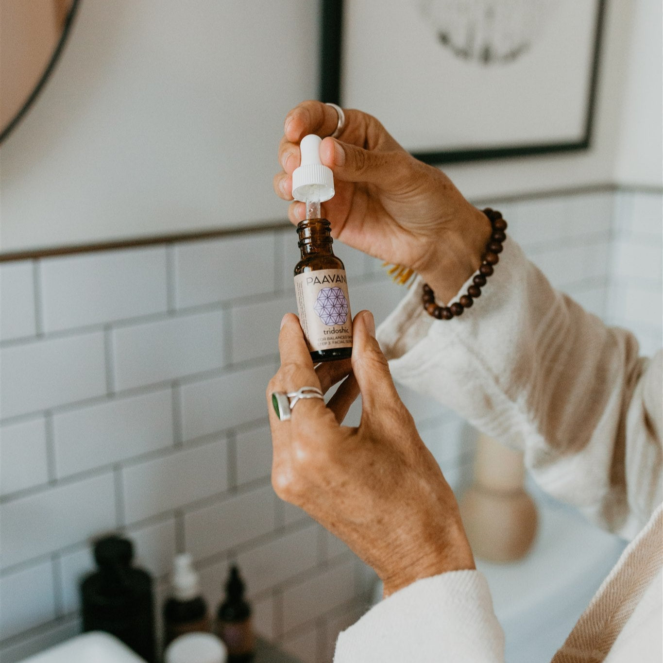 Person holding a bottle of serum with a blurred bathroom background