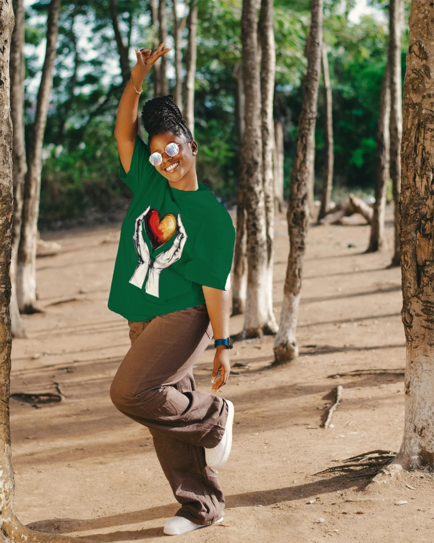 Person wearing a green shirt with a colorful design, standing in a forested area.