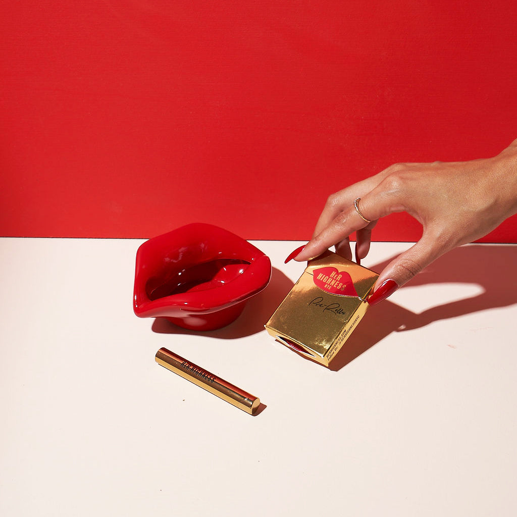 Hand holding a gold product packaging with a red background