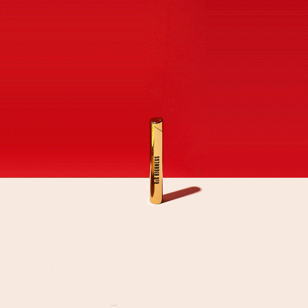 Gold cylindrical object with 'HER Highness' text on a red and beige background