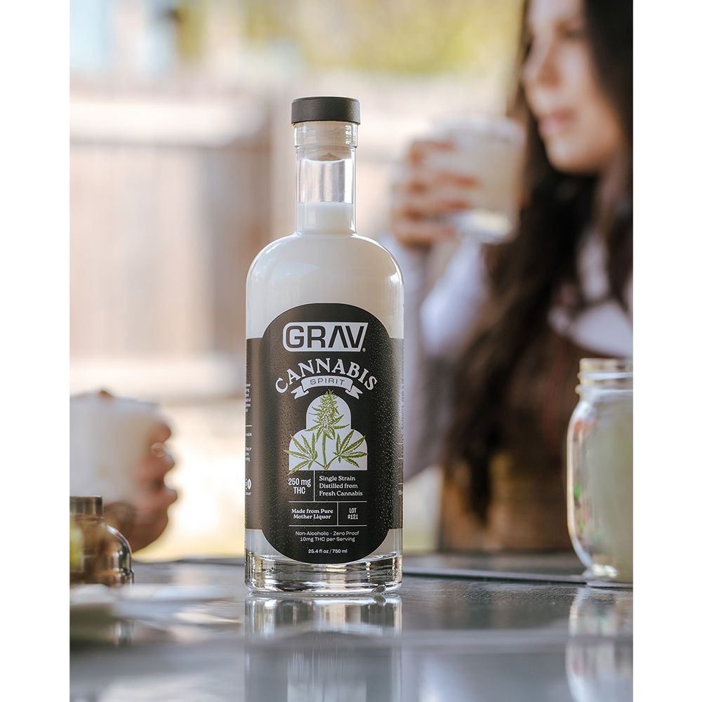 Grav Cannabis bottle on a table with a blurred background of people and a drink.