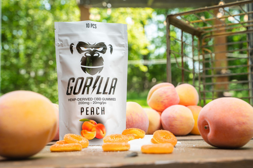 Packaging of Gorilla Peach CBD gummies with peaches on a wooden table outdoors.