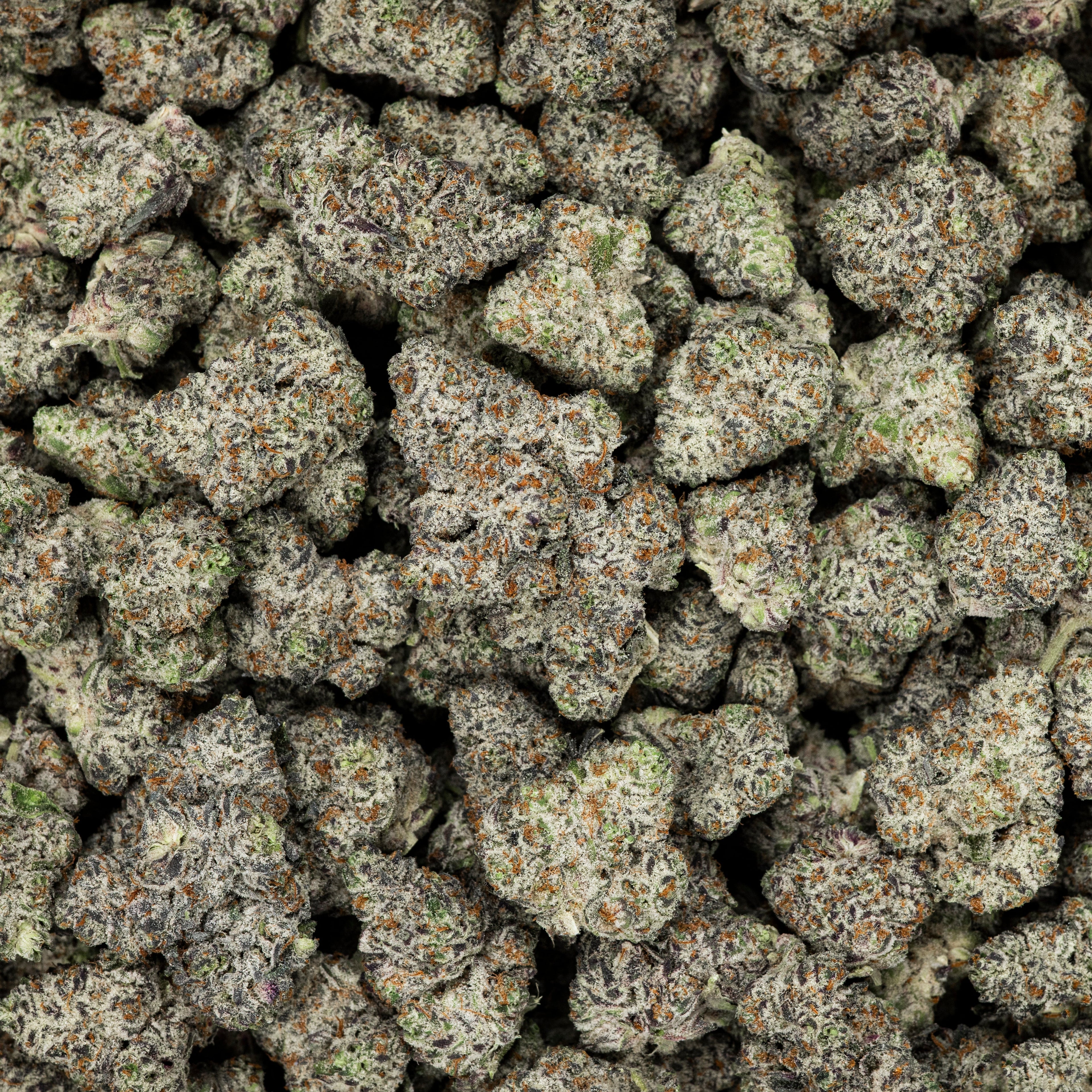 Close-up of a pile of cannabis buds with green and brown colors.