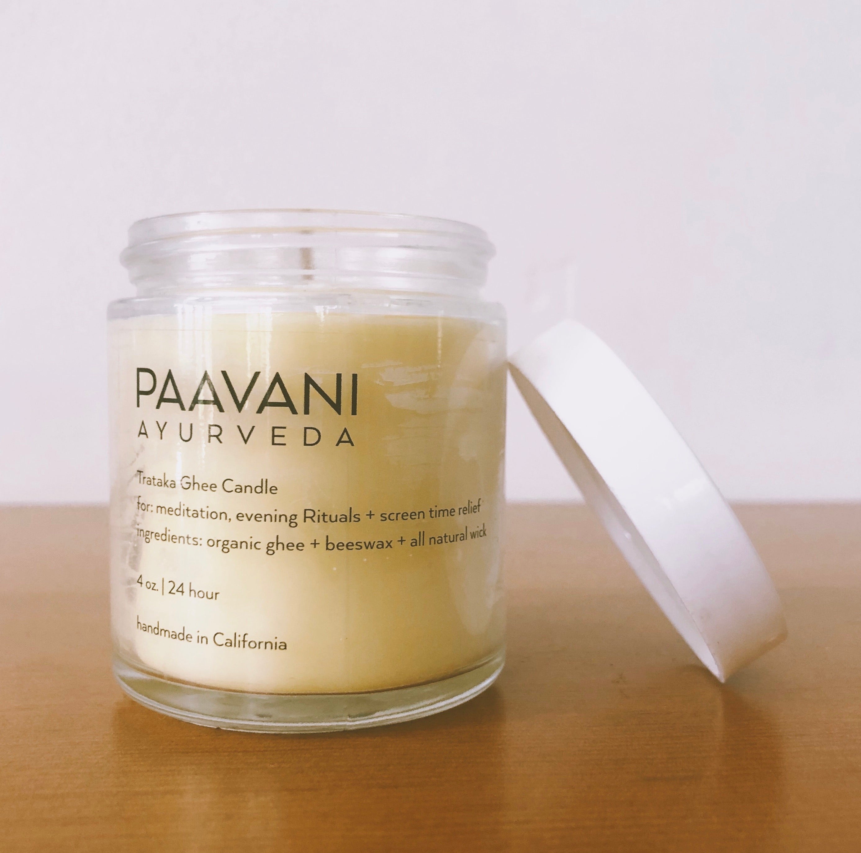 PAAVANI AYURVEDA candle in a glass jar on a wooden surface with a white background